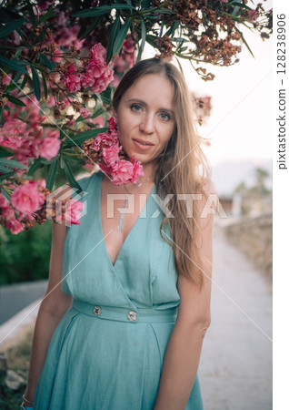 Elegant Woman Posing with Pink Flowers Outdoors 128238906