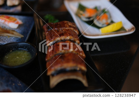 Chopsticks smoked eel Stylish black sushi set on a flat plate with different kinds of roll, nigiri, maki, gunkan. Japanese national cuisine close up view 128238947