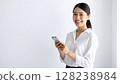 A smiling woman holding a smartphone in her hand. A clean and bright image. 128238984