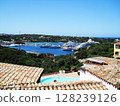 Stunning panoramic view of Porto Cervo, a luxurious seaside resort on the Costa Smeralda in northern Sardinia, Italy. The image features a picturesque harbor filled with elegant white yachts and 128239126