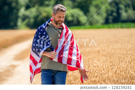 Man with American flag in crop field. Independence day of America. 4th of July. American labor day. American flag and man farmer. Flag of USA. Independence day. Man in field, advertisement Man with American flag in crop field. Independence day of America. 4th of July. American labor day. American flag and man farmer. Flag of USA. Independence day. Man in field, advertisement 128239281