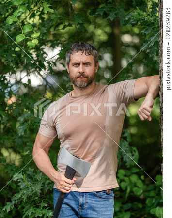 Sweating guy relax. Handsome man with axe. Lumberjack in woods with an ax. Lumberjack in shirt with heavy axe. Strong man work in forest. Lumberjack men in forest with axe. Lumberjack carries axe 128239283