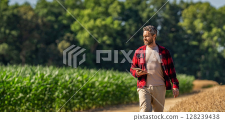 Farmer agronomist man with tablet in cornfield. Technology of modern agriculture. Farmer man working on field with tablet. Hispanic farmer with tablet check harvest. Crop harvest. Copy space banner Farmer agronomist man with tablet in cornfield. Technology of modern agriculture. Farmer man working on field with tablet. Hispanic farmer with tablet check harvest. Crop harvest. Copy space banner 128239438
