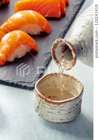 Sake poured into ochoko, traditional cup, with salmon Sake poured into ochoko, traditional cup, with salmon 128241419