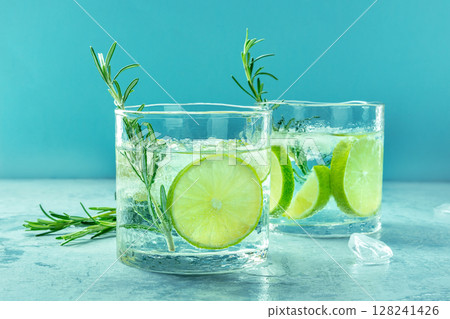Gin tonic glasses, side view with rosemary and lime. Fresh summer cocktail Gin tonic glasses, side view with rosemary and lime. Fresh summer cocktail 128241426