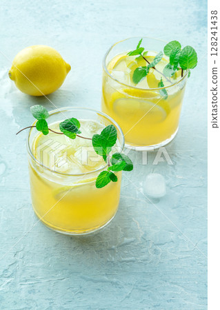 Glasses of lemonade with fresh mint, a mocktail with lemon juice, on blue Glasses of lemonade with fresh mint, a mocktail with lemon juice, on blue 128241438