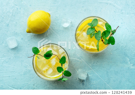 Glasses of lemonade, a mocktail with lemon juice, on a blue background Glasses of lemonade, a mocktail with lemon juice, on a blue background 128241439