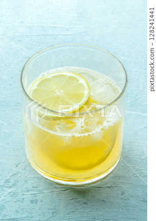 A glass of lemonade, a mocktail with lemon juice, on a blue background 128241441