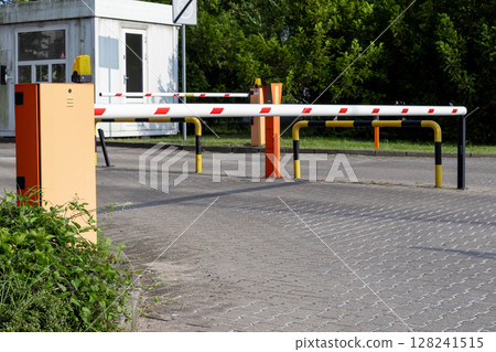 Automated parking barrier with a lowered arm and security booth, effectively managing vehicle access and site security at an an entry point 128241515