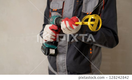 Construction worker holding cordless drill and mixing paddle attachment 128242842