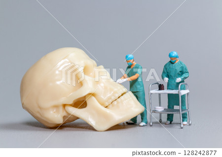 Miniature Surgeons Operating on Human Skull Model Miniature Surgeons Operating on Human Skull Model 128242877