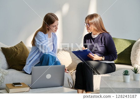 Serious teen girl in session in office of professional psychologist, therapist 128243187