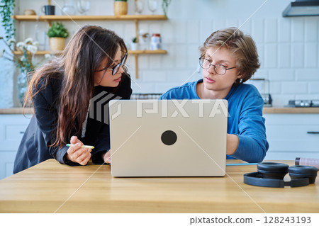 Teenage boy student with female mentor trainer teacher looking at laptop computer screen Teenage boy student with female mentor trainer teacher looking at laptop computer screen 128243193