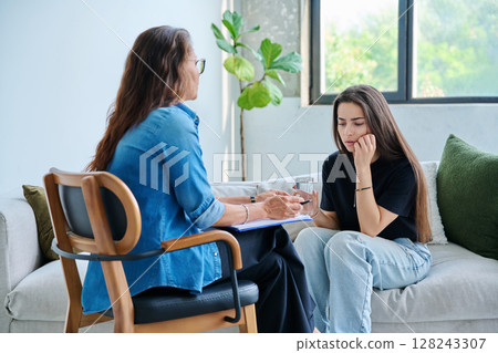 Sad teenage girl student talking with social psychologist, therapist, counselor Sad teenage girl student talking with social psychologist, therapist, counselor 128243307