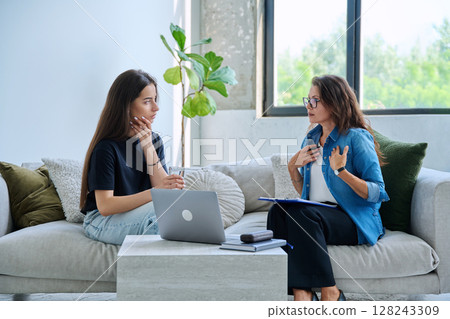 Serious teen girl in session in office of professional psychologist, therapist 128243309