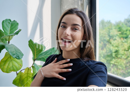 Close-up selfie portrait of teenage female looking at web camera 128243320
