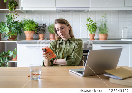 Restless woman scroll phone, taking laptop work pause at home. Unfocused internet browsing, chatting 128243352