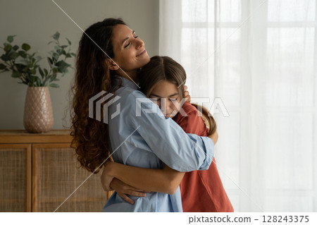 Young loving mother hugging teenage daughter at home, mom cuddling supporting upset teen girl Young loving mother hugging teenage daughter at home, mom cuddling supporting upset teen girl 128243375