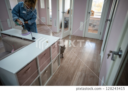 Woman staff member weighs cat food, ensuring accurate portion in grams for feeding in pet hotel Woman staff member weighs cat food, ensuring accurate portion in grams for feeding in pet hotel 128243415
