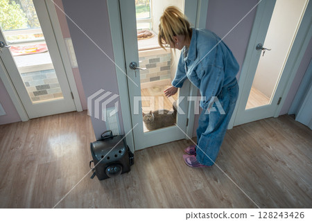 Female owner rests on glass door of cat hotel room. Pet accommodations for safe, cat service Female owner rests on glass door of cat hotel room. Pet accommodations for safe, cat service 128243426