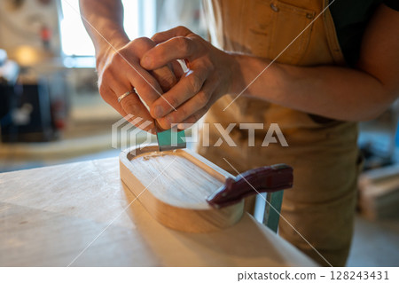 Carpenter hands focus on finishing polish sanding drink coaster for bottles glasses with sandpaper 128243431