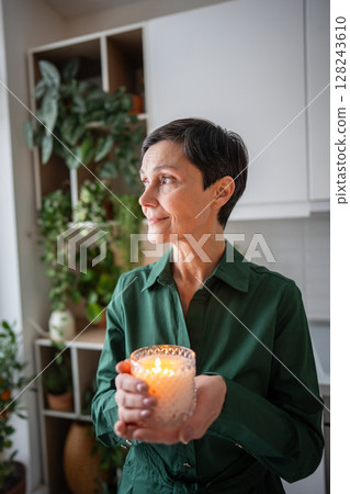 Peaceful woman enjoying candle aroma after daily routine. Mindfulness, self care ritual, slow life 128243610