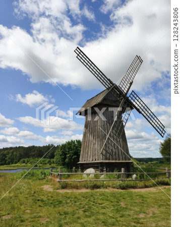 An old wooden windmill on a summer day. Mikhailovskoye Estate. Pushkin Hills, Russia. Landmark, vertical photo. 128243806