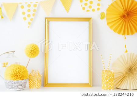 Vertical golden frame on white wall with festive yellow paper decorations, polka dot bunting and party elements. Bright and cheerful celebration mockup for birthday or event design. Copy space 128244216