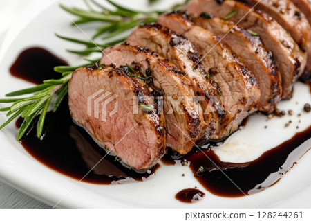 Gourmet medium-rare beef steak sliced and served with rosemary sprigs and balsamic glaze on white plate. High-end restaurant cuisine, perfect for menu design and food marketing visuals. Copy space 128244261