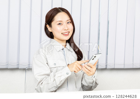 Woman in work clothes operating a smartphone 02 128244628