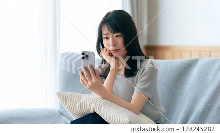 一位女士一邊看著智慧型手機一邊思考 128245282