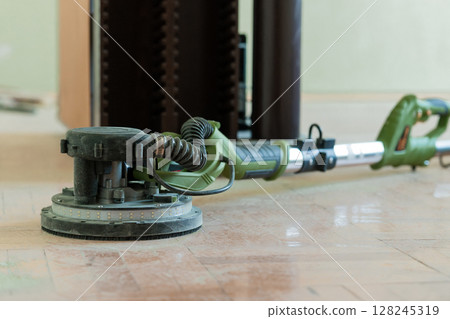 Floor Sanding Process with Green Drywall Sander, Dust Extraction Hose, and Polished Marble Tile Flooring in Home Renovation Project Floor Sanding Process with Green Drywall Sander, Dust Extraction Hose, and Polished Marble Tile Flooring in Home Renovation Project 128245319