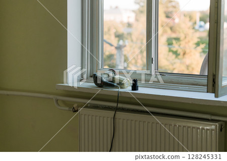 Vintage Camera on Window Sill During Home Renovation: Yellow Interior with Green View, Power Tool, Radiator, Pipes, Natural Light Vintage Camera on Window Sill During Home Renovation: Yellow Interior with Green View, Power Tool, Radiator, Pipes, Natural Light 128245331
