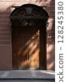 A beautifully crafted Elegant Wooden Door adorned with Exquisite Intricate Ironwork detailing 128245380