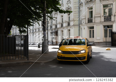 A bright yellow taxi cab is making a turn at a busy urban intersection in the city A bright yellow taxi cab is making a turn at a busy urban intersection in the city 128245382