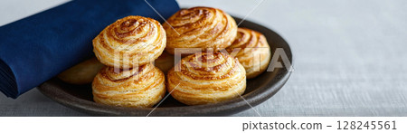 Delicious golden-brown pastries served on a rustic plate with a blue napkin. Delicious golden-brown pastries served on a rustic plate with a blue napkin. 128245561