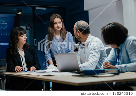 Young female colleague arriving late to business meeting in office 128245810