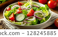 fresh garden salad in a white bowl, with crisp romaine lettuce, sliced cucumber, halved cherry tomatoes 128245885