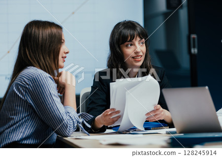 Female colleagues listening attentively to opinion during business meeting in office 128245914