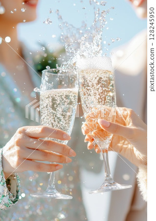 Refined businesswomen clinking champagne glasses, laughing together against sunlit urban backdrop, expressing camaraderie and professional success 128245950