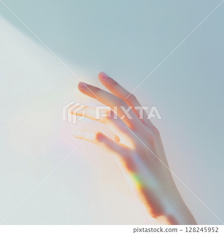 Female hand extending toward bright light, casting prismatic rainbow reflection across skin, representing spiritual connection and inner hope 128245952