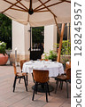 An Elegant Outdoor Dining Setup Featuring Stylish Umbrella and Comfortable Chairs 128245957
