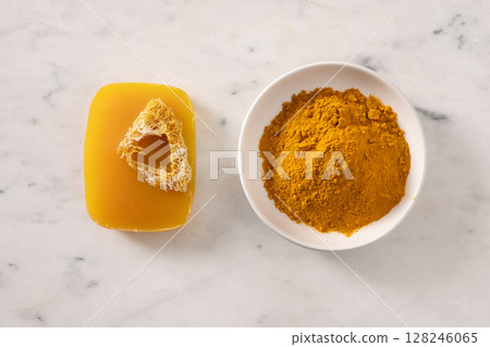 Turmeric soap bar and powder turmeric root on marble white background. Organic skincare product perfect for wellness, beauty, and organic body care concepts. View from above. 128246065