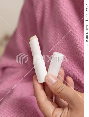 Woman in pink bathrobe holding in hand opened lip balm stick with a lid closeup, girly mockup Woman in pink bathrobe holding in hand opened lip balm stick with a lid closeup, girly mockup 128246647