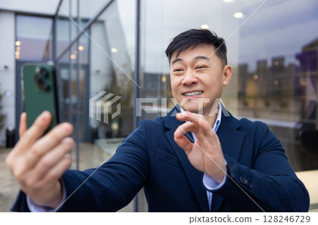 Young asian man in a suit with a phone in hand Young asian man in a suit with a phone in hand 128246729