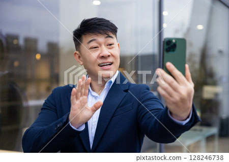Young asian man in a suit with a phone in hand Young asian man in a suit with a phone in hand 128246738