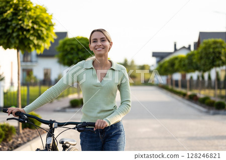 Woman preparing for bike ride on residential path near homes 128246821