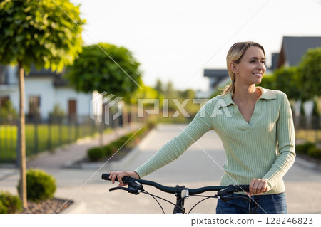 Woman preparing for bike ride on residential path near homes Woman preparing for bike ride on residential path near homes 128246823