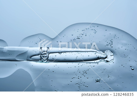 Transparent serum with bubbles and dropper dropper on a blue background. 128246835