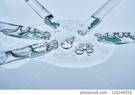 The serum flows from several pipettes into a single texture on a blue background. The serum flows from several pipettes into a single texture on a blue background. 128246838